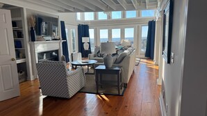 Un salon spacieux doté d’une cheminée, d’un téléviseur et d’une grande fenêtre donnant sur l’extérieur.