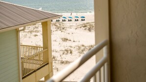 Un balcon avec vue sur la plage, comprenant des chaises longues et des parasols.