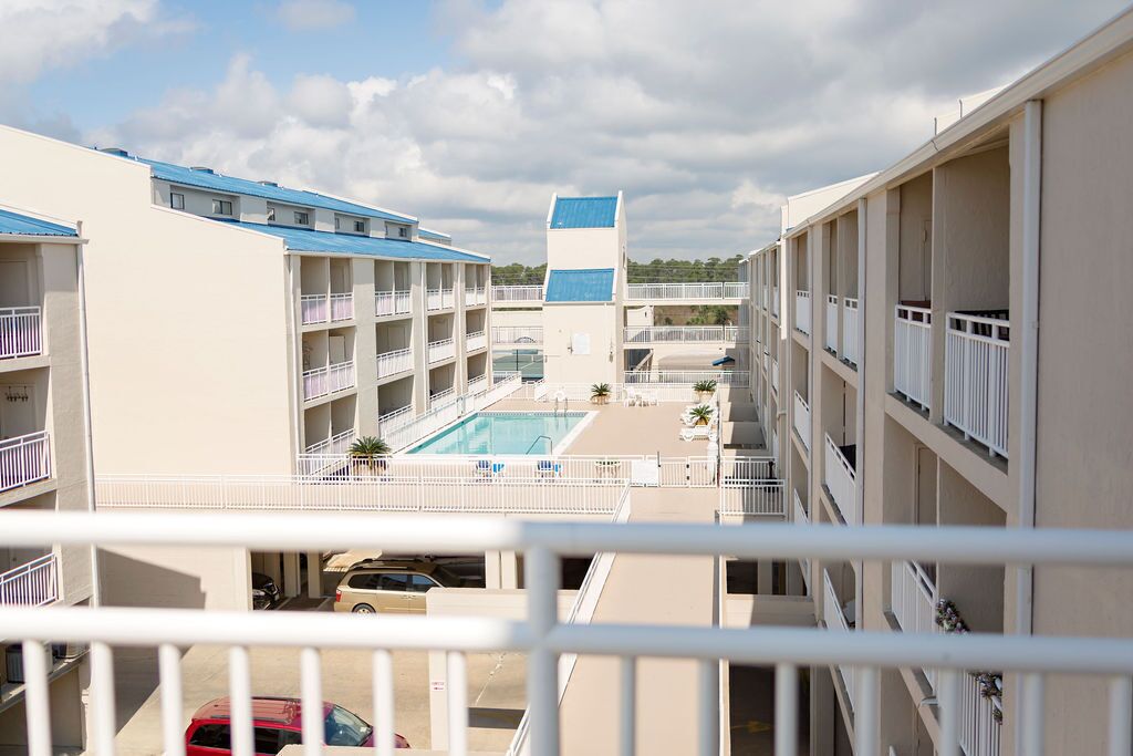 A multi-story hotel with balconies, a swimming pool, and a parking area.