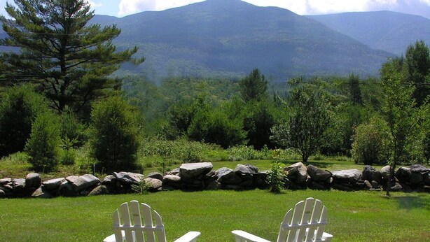 Two Adirondack chairs with green cushions in a grassy area with a mountain view. - CHARMING, 4-Br, 2-Ba, Full Kitchen Wi-Fi, Mt View, private deck, discounts avail (Franconia)