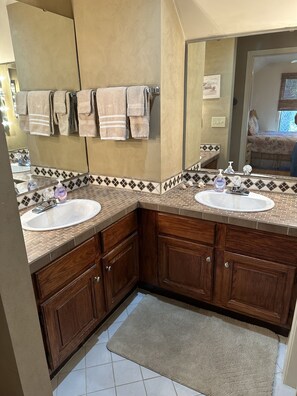 A bathroom with two sinks, wooden cabinets, a mirror, and a tiled backsplash. - Turtle Cove Open Floor Plan 2bed/2bath Turtle Cove Villa Pet Friendly (Kiawah Island)