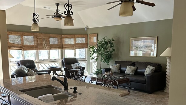 Een keuken met een groot eiland, een RVS vaatwasser en donkerhouten kasten.