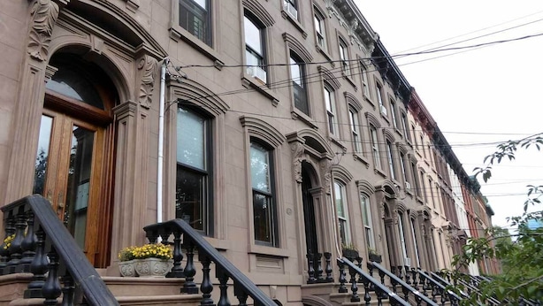 A multi-story building with a grand entrance, a staircase with balustrades, and a row of windows. - Close to NYC in Historic Brownstone (Jersey City)