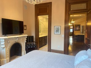 Una camera da letto con un letto grande, un camino, una TV e vista sul bagno.