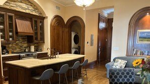 A modern kitchen with a large island, bar stools, and a dining table. - Close to NYC in Historic Brownstone (Jersey City)
