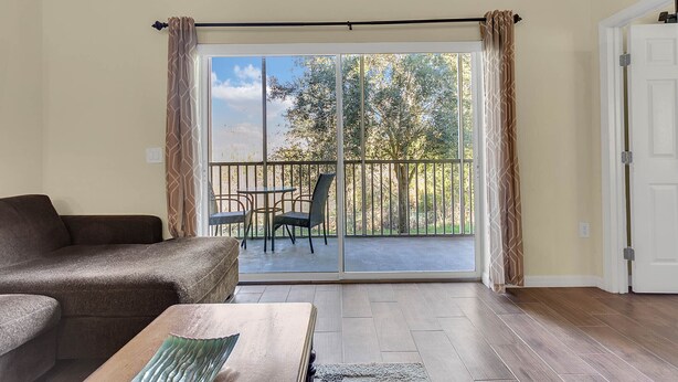 Een woonkamer met een bank, een salontafel en een balkon met een tafel en stoelen.