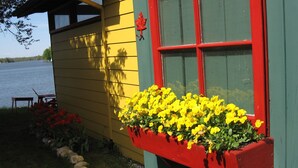 Un edificio amarillo con una caja de ventana roja llena de flores amarillas.