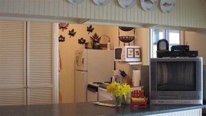 Una cocina con refrigerador, microondas, estufa y televisor.