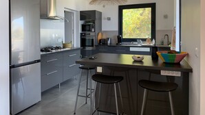 A modern kitchen with stainless steel appliances, a large window, and a bar area.