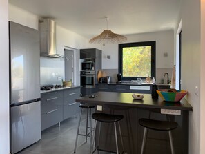Cozinha moderna com eletrodomésticos de aço inoxidável, uma janela ampla e um espaço bar.