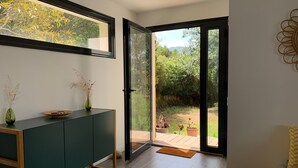 A modern interior with a green cabinet, a large window, and a view of a garden.