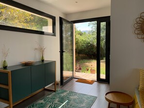 Um interior moderno com um armário verde, uma janela grande e vista para um jardim.