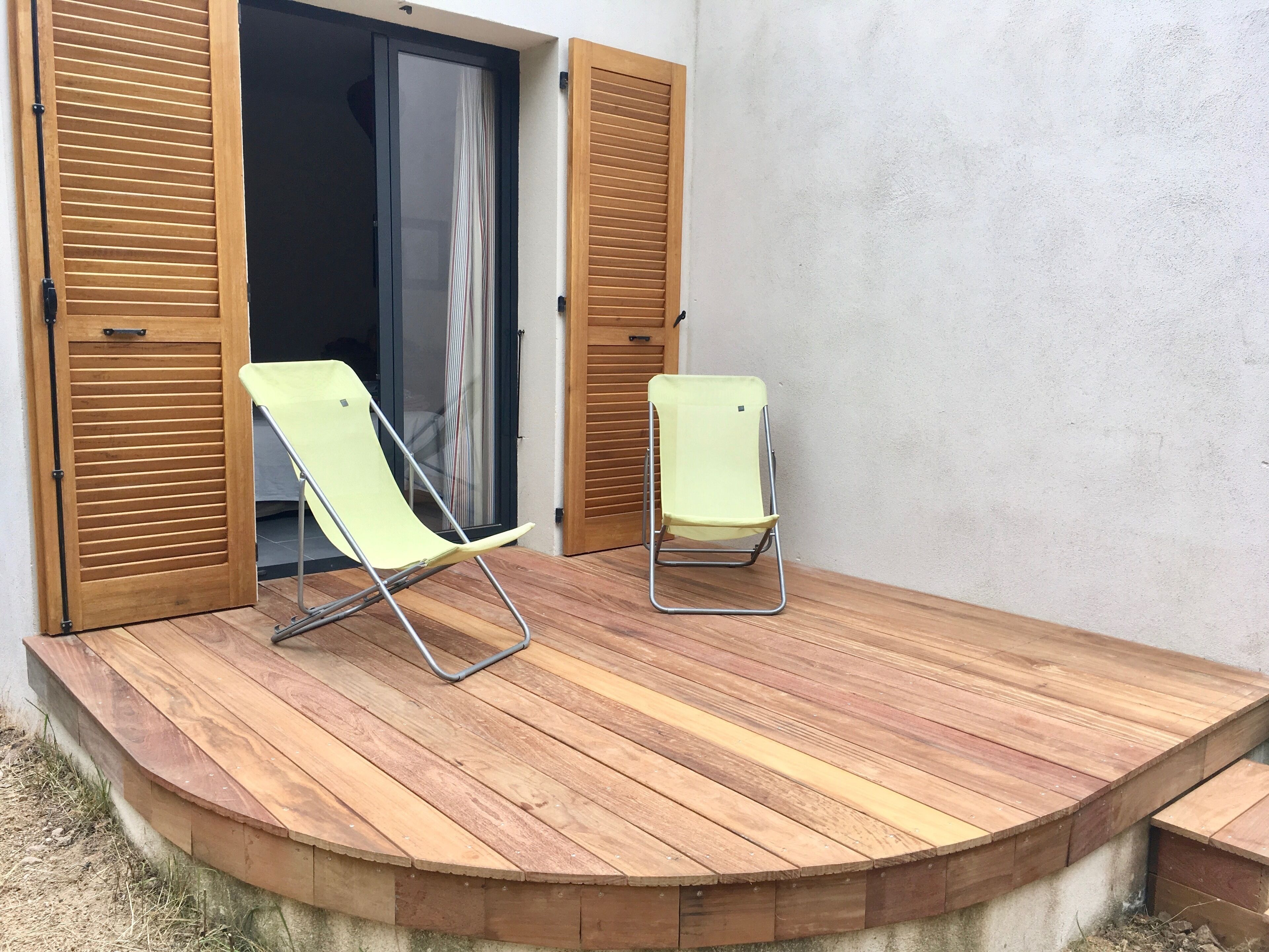 A wooden deck with two folding chairs and a sliding glass door.