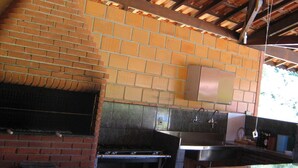 An outdoor kitchen with a brick wall, a stainless steel sink, and a grill. - CHACARA HORTOLAN, BEAUTIFUL AND COZY FOR SPECIAL MOMENTS (ITU)