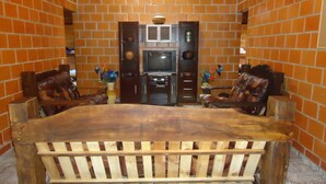 A dining area with a wooden table and chairs, brick walls, and a television. - CHACARA HORTOLAN, BEAUTIFUL AND COZY FOR SPECIAL MOMENTS (ITU)