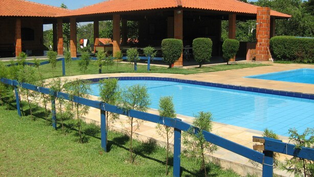 A swimming pool with a blue border, surrounded by a blue fence and small trees. - CHACARA HORTOLAN, BEAUTIFUL AND COZY FOR SPECIAL MOMENTS (ITU)
