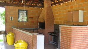 A brick-built outdoor kitchen area with a chimney, a white refrigerator, and two yellow trash bins. - CHACARA HORTOLAN, BEAUTIFUL AND COZY FOR SPECIAL MOMENTS (ITU)