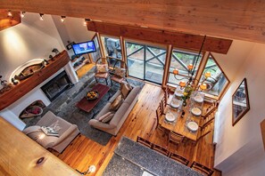 A spacious living area with a fireplace, a sofa, a dining table set for four, and a television mounted on the wall. - Pinnacle Ridge, 3 Bedroom + Den (Whistler)