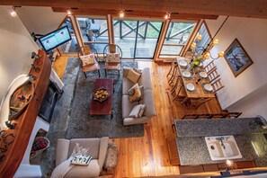 A cozy interior with a wooden dining table, a sofa, a TV, and a kitchen area. - Pinnacle Ridge, 3 Bedroom + Den (Whistler)