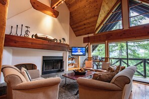 A cozy living room with a fireplace, comfortable seating, and a television. - Pinnacle Ridge, 3 Bedroom + Den (Whistler)