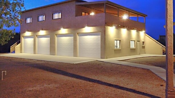 A modern two-story building with multiple garage doors, a flat roof, and a covered balcony area. - Large Balcony, Exceptional Views. (Tucson)