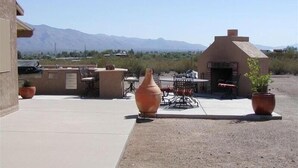 An outdoor patio with a barbecue area, a table with chairs, and large terracotta pots. - Large Balcony, Exceptional Views. (Tucson)