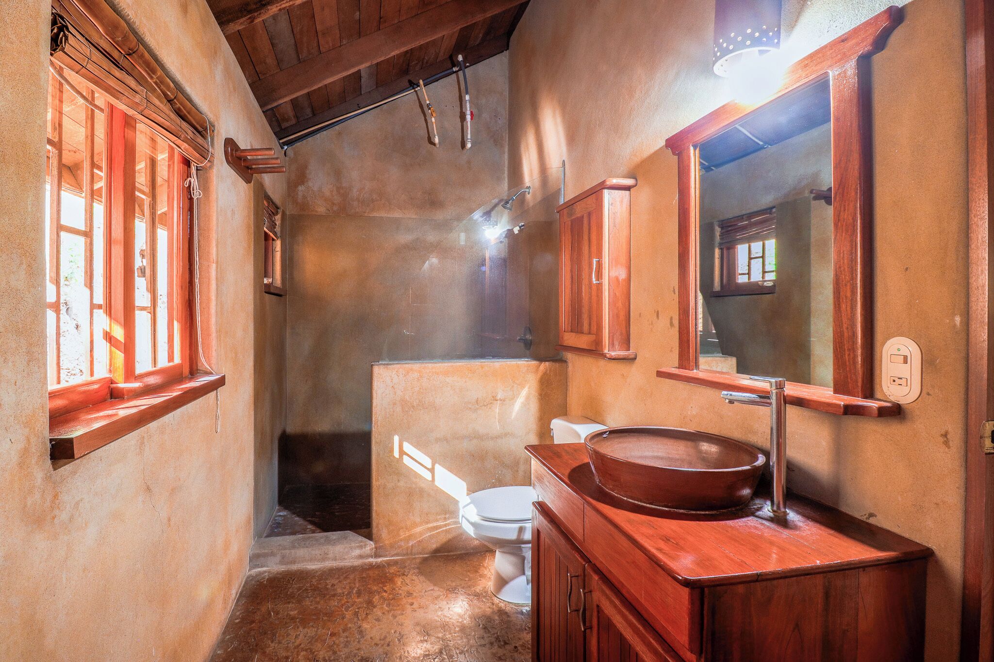 A bathroom with a wooden vanity, a large mirror, and a white toilet.