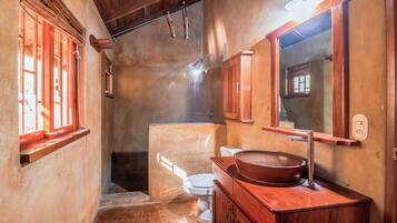 A bathroom with a wooden vanity, a large mirror, and a white toilet.