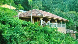 A house with a tiled roof, surrounded by lush greenery. - Casa Sueños: Stunning Bay-view Retreat • Infinity Pool • Walk to Town • Sleeps 9 (San Juan Del Sur)