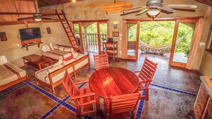 A spacious living area with a wooden dining table and chairs, a sofa, a TV, and a hammock outside. - Casa Sueños: Stunning Bay-view Retreat • Infinity Pool • Walk to Town • Sleeps 9 (San Juan Del Sur)