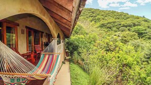 A balcony with a hammock and a view of a lush green hillside. - Casa Sueños: Stunning Bay-view Retreat • Infinity Pool • Walk to Town • Sleeps 9 (San Juan Del Sur)