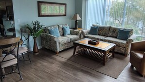 A living room with a sofa set, a coffee table, and a dining area with chairs and a table.