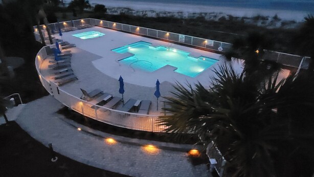 A pool area with multiple swimming pools, lounge chairs, and umbrellas.