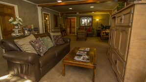 A living room with a brown leather sofa, a wooden coffee table with magazines, and a wooden cabinet.