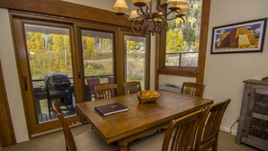 A dining area with a wooden table and chairs, a laptop, and a basket.