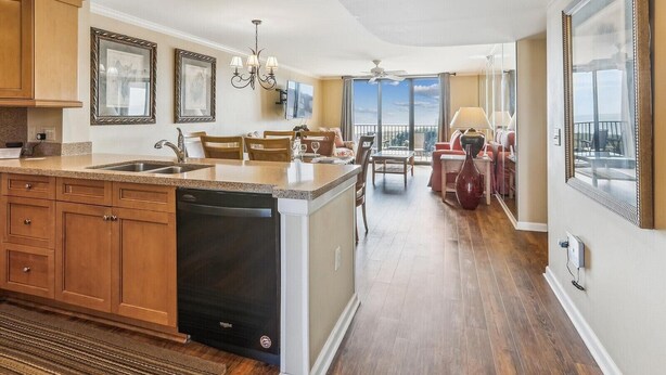 A spacious kitchen with a dishwasher, a dining area with a chandelier, and a view of the outdoors through large windows. - Top Floor Condo. Beautiful Ocean Views. Great Mid-Island Location (Hilton Head Island)