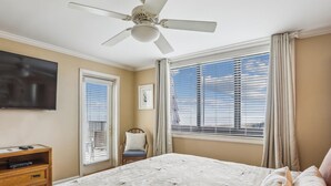 A hotel room with a bed, a ceiling fan, a TV, a window with blinds, and a chair. - Top Floor Condo. Beautiful Ocean Views. Great Mid-Island Location (Hilton Head Island)