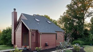 A small, single-story house with a sloped roof, a chimney, and a front door.