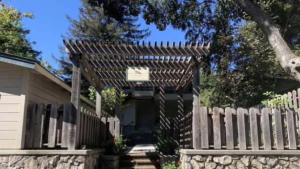 Unes escales de pedra que condueixen a una pérgola de fusta amb un cartell.