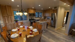 Eine moderne Küche mit Holzschränken, einem Edelstahlkühlschrank und einem Essbereich mit Holztisch und Stühlen.