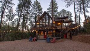 Eine zweistöckige Lodge mit Balkon, Sitzgelegenheiten im Freien und Lichterketten.