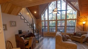 Ein geräumiger Wohnbereich mit einer Holztreppe, einem Schreibtisch und zwei Sofas.