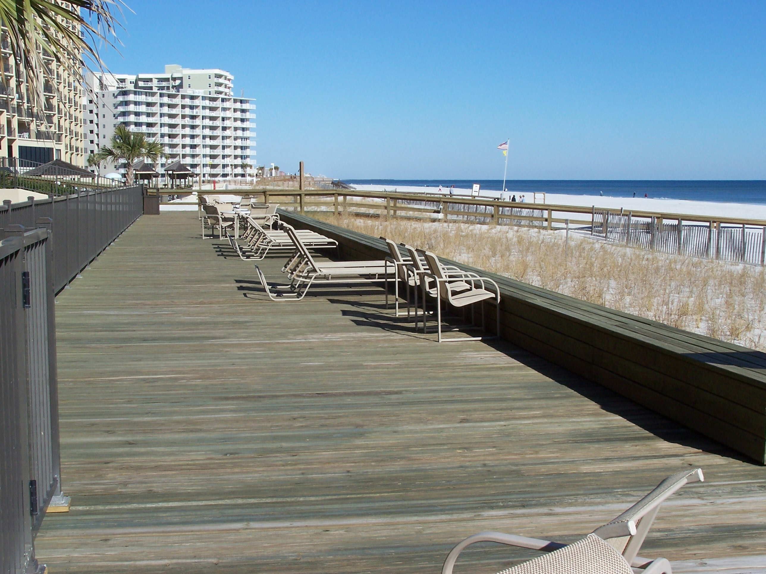 A wooden boardwalk with beach chairs and a view of the ocean.