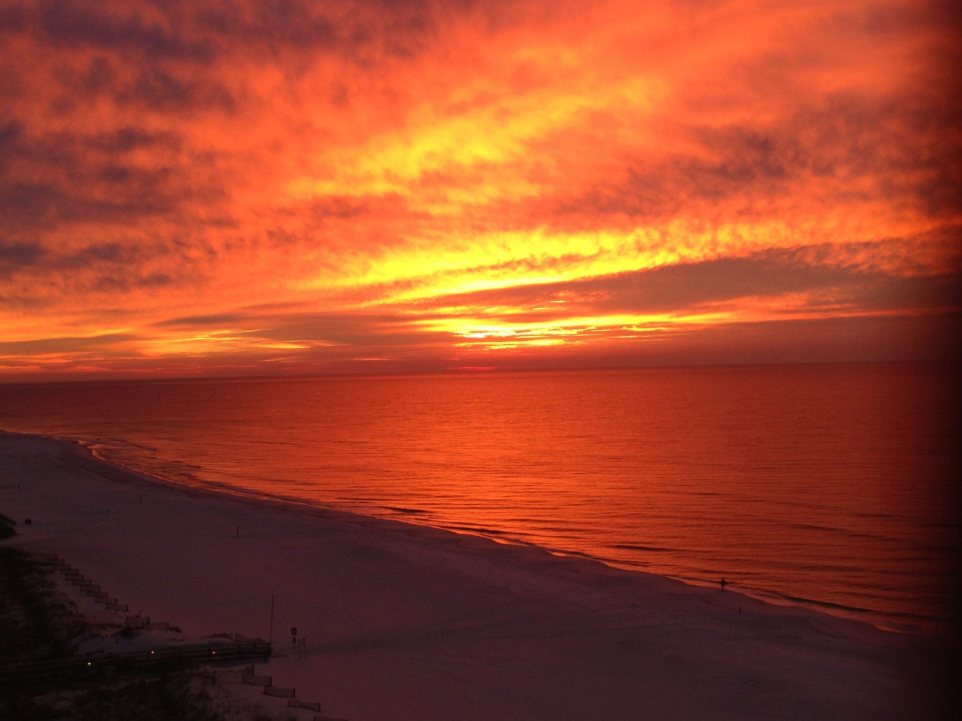 A sunset over a beach with a clear sky.