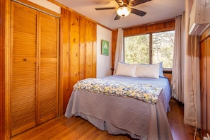 A bedroom with a bed, wooden walls, a ceiling fan, and a window with curtains. - The Kaweah River Cabin sleeps up to 8 guests, located 3 minutes from entrance (Three Rivers)