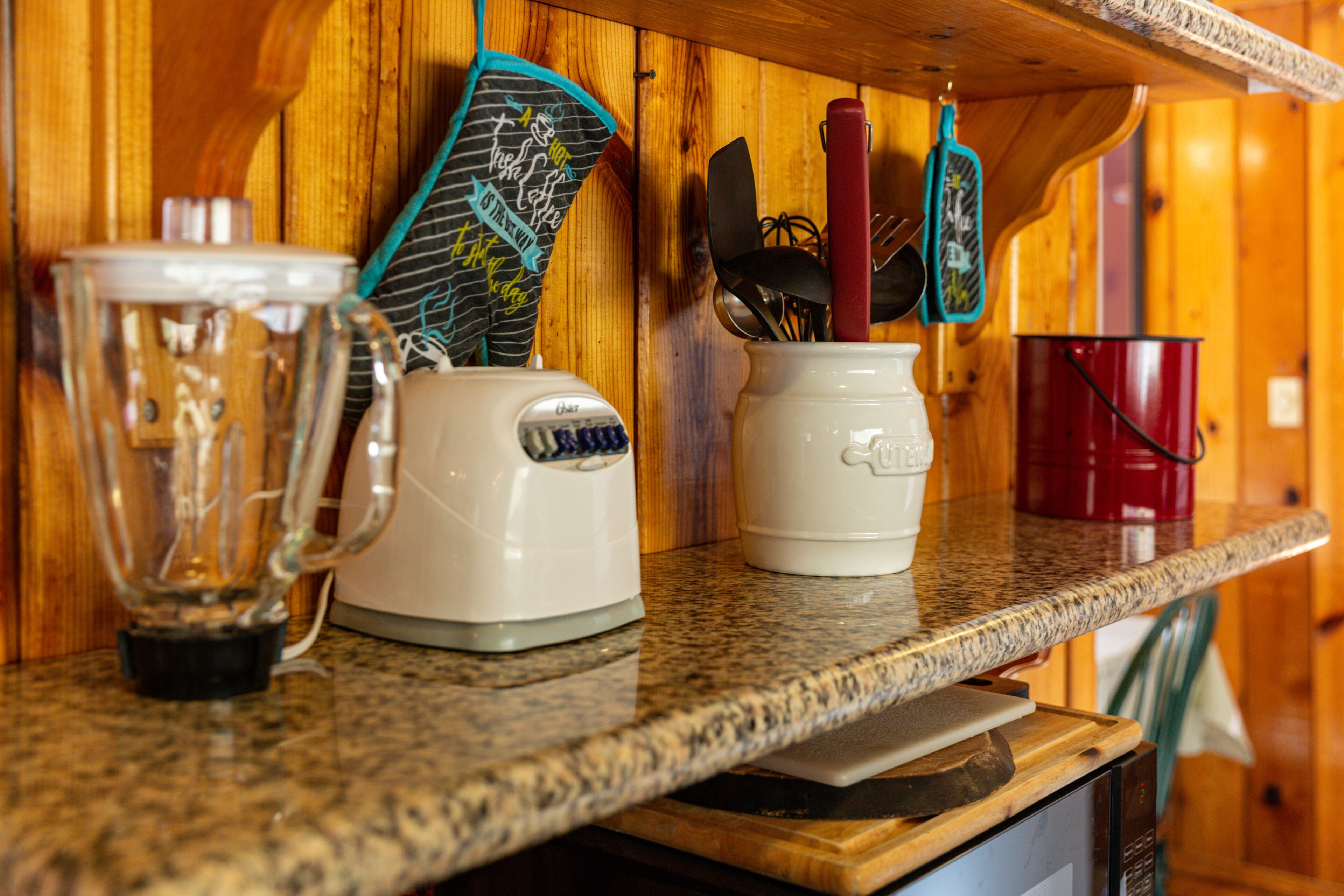 A kitchen counter with a blender, a coffee maker, and a mug.