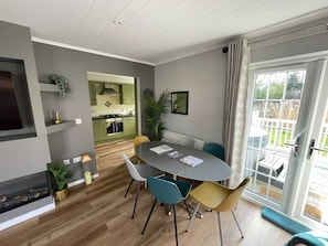 A modern kitchen with green cabinets, a dining area with a round table and chairs, and a sliding glass door to the outside.