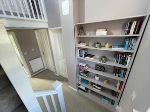 A room with a bookshelf, a white chair, and a door leading to another room.