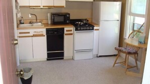 A compact kitchen with white cabinets, a microwave, a stove, and a refrigerator. - Cozy studio in St. Joseph, Michigan (St Joseph)