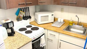 A kitchen with a stove, microwave, sink, and various utensils.